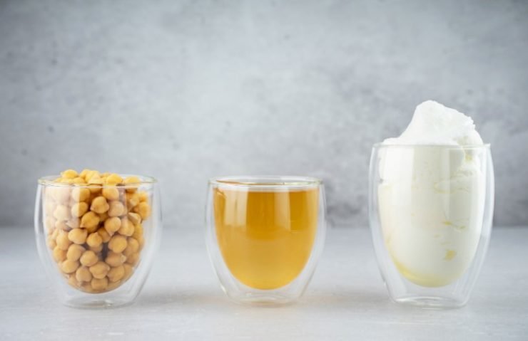 Chickpea aquafaba. Egg replacement. Vegan cooking concept. Chickpea, chickpea water, whipped chickpeas liquid, called aquafaba, in glass cup. On a gray background. Sustainable. Natural products