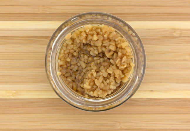 Open jar of garlic on a cutting board