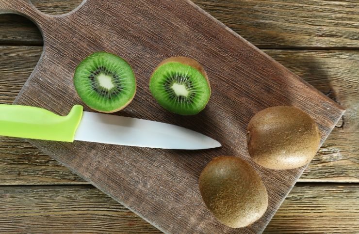 Kiwi with Knife on Cutting Board on Wooden Background