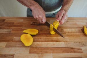 person cutting mango sides