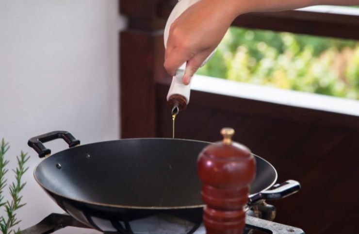 Pouring olive oil into wok.
