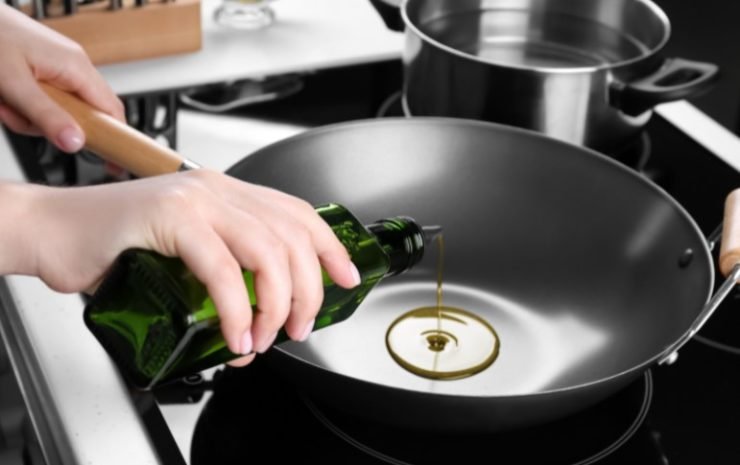woman oiling a black wok 