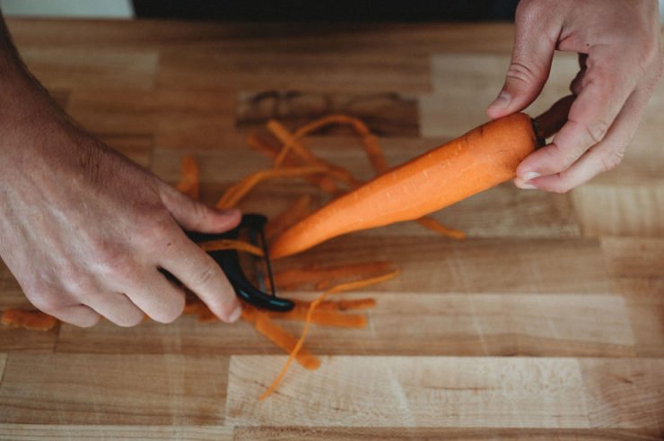 person peeling carrots with peeler