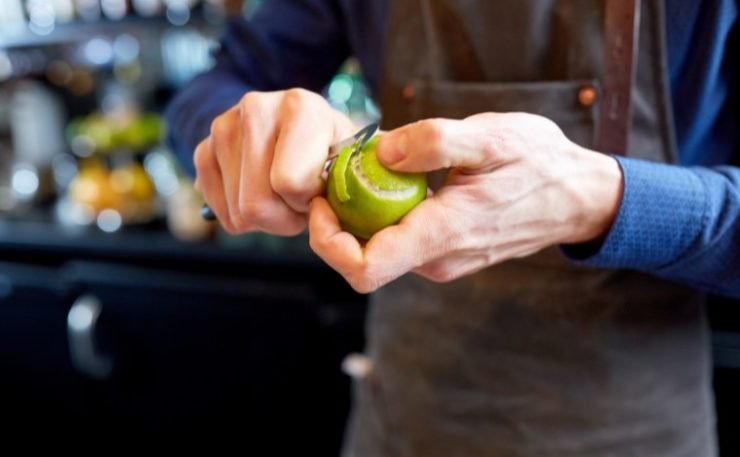 Bartender Removing Peel from Lime at Bar